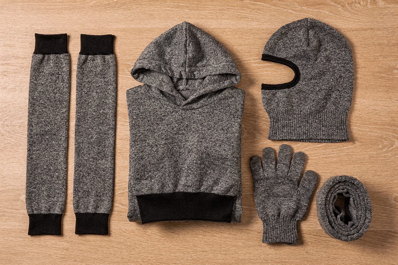 Illustration: a flat lay of gray cut-resistant knitwear with a hoodie, oversleeves, a balaclava and a glove
